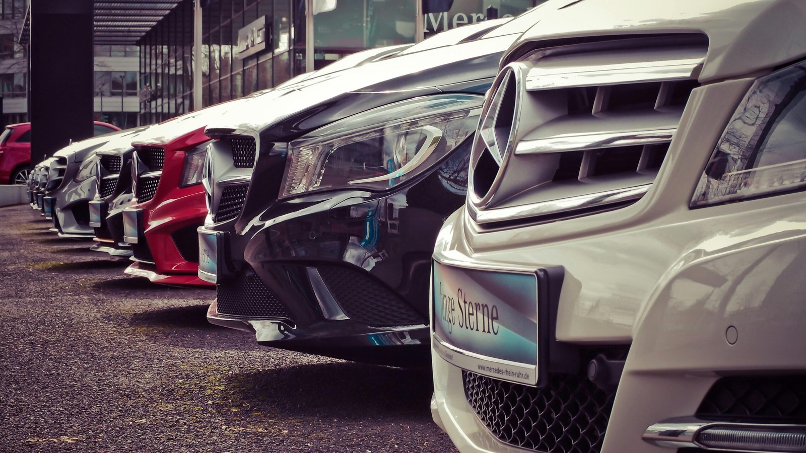 Luxury cars lined up at an outdoor dealership, showcasing sleek designs.